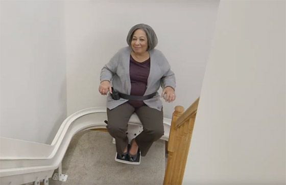 Lady on Bruno Elite Curved stairlift going-up stairs